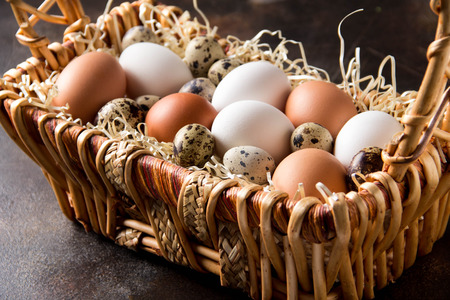 Different eggs in the basket, white, dark, quail and chicken. Easter holidayの写真素材