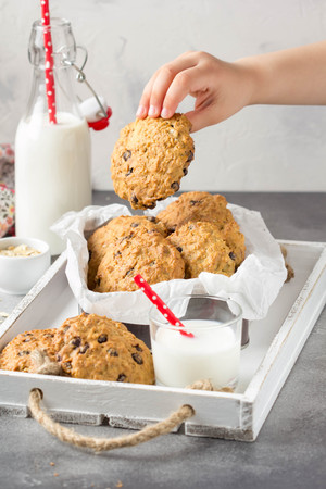 Homemade oatmeal cookies with chocolate and banana, milk in a glass with a straw, kids hands. Delicious dessert, Breakfast (lunch), healthy food, pastriesの写真素材