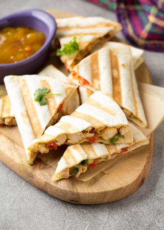 Mexican quesadilla with chicken, tomatoes, cheese and grilled sauce. Tasty snack in a pellet, healthy foodの写真素材