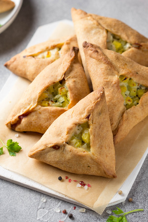 Tatar pie triangle echpochmak, Russian kurnik, delicious pastry with chicken and potatoes. Traditional food, quick snack of doughの写真素材