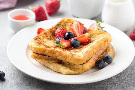 French toast with berries (blueberries, strawberries) and sauce, traditional sweet dessert of bread with egg and milk. Morning baking foodの写真素材