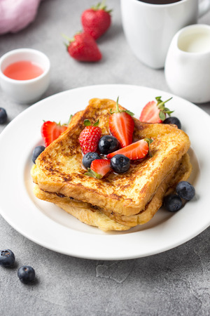 French toast with berries (blueberries, strawberries) and sauce, traditional sweet dessert of bread with egg and milk. Morning baking foodの写真素材