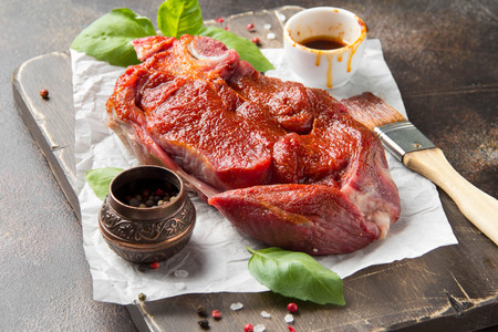 Raw beef on bone, cooking steak with spices, barbecue marinade, red sauce. Traditional food, uncooked meat on Boardの写真素材