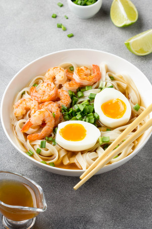 Japanese soup with wheat noodles, fried shrimp, soft-boiled egg with liquid yolk and green onions. Traditional Asian ramen, delicious lunch, healthy foodの写真素材