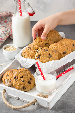 Homemade oatmeal cookies with chocolate and banana, milk in a glass with a straw, kids hands. Delicious dessert, Breakfast (lunch), healthy food, pastriesの写真素材