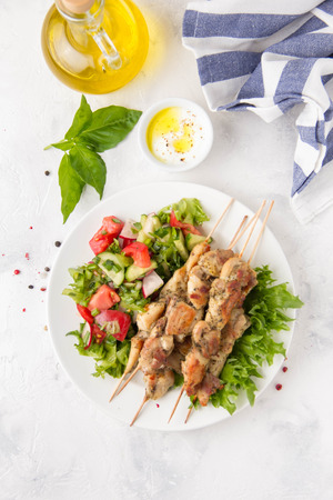 Meat kebabs (chicken, Turkey, pork) on wooden skewers with vegetable salad and yogurt sauce. Spring picnic, grilled food, delicious lunch. On light backgroundの写真素材