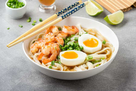 Japanese soup with wheat noodles, fried shrimp, soft-boiled egg with liquid yolk and green onions. Traditional Asian ramen, delicious lunch, healthy foodの写真素材