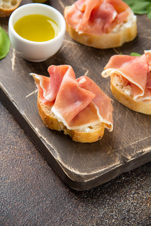 Toast with serrano ham (jamon, prosciutto crudo, hamon), traditional Italian antipasti. Delicious snack with bread, cream cheese, olives. Health food, appetizer for wine, bruschettaの写真素材