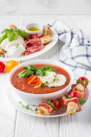 Tomato cold gazpacho soup with fresh vegetables, mozzarella, salami, croutons and basil. Traditional Spanish summer foodの写真素材