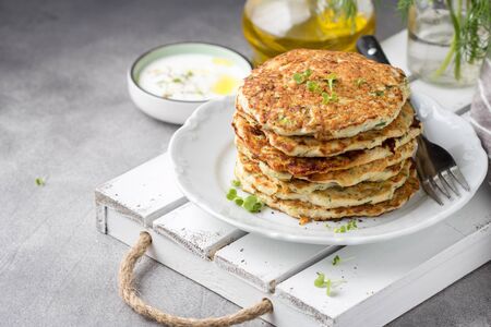 Chicken pancakes with zucchini and herbs, stack of cutlets on plate. Delicious summer food, healthy lunch with meat, vegetables and yogurt sauceの写真素材