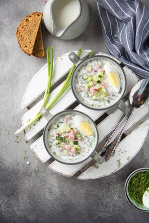 Traditional cold Russian soup okroshka, with sausage (ham), potatoes, boiled egg, fresh vegetables (cucumber, radish), green onions and dill. Yogurt, kefir, mineral water. Summer foodの写真素材