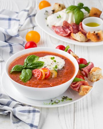 Tomato cold gazpacho soup with fresh vegetables, mozzarella, salami, croutons and basil. Traditional Spanish summer foodの写真素材