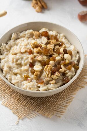 Oatmeal with nuts (hazelnuts, walnuts) and honey, porridge for Breakfast. Tasty and healthy foodの写真素材