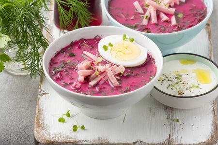 Cold beet soup, traditional Lithuanian dish, summer food. Fresh vegetables (cucumbers, radishes, green onions, cilantro), sour cream, yogurt, egg, hamの写真素材