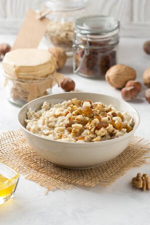 Oatmeal with nuts (hazelnuts, walnuts) and honey, porridge for Breakfast. Tasty and healthy foodの写真素材
