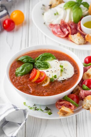 Tomato cold gazpacho soup with fresh vegetables, mozzarella, salami, croutons and basil. Traditional Spanish summer foodの写真素材