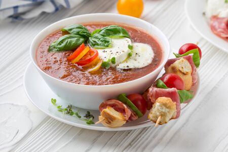 Tomato cold gazpacho soup with fresh vegetables, mozzarella, salami, croutons and basil. Traditional...
