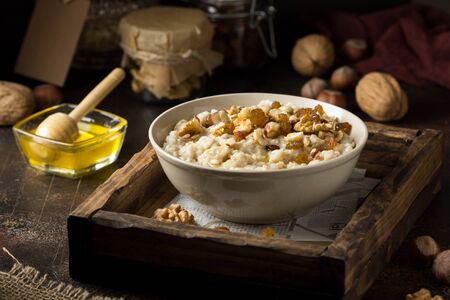 Oatmeal with nuts (hazelnuts, walnuts) and honey, porridge for Breakfast. Tasty and healthy foodの写真素材