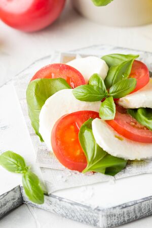 Caprese salad with mozzarella, juicy tomato and fresh Basil. A delicious Italian snack, traditional food. On light backgroundの写真素材