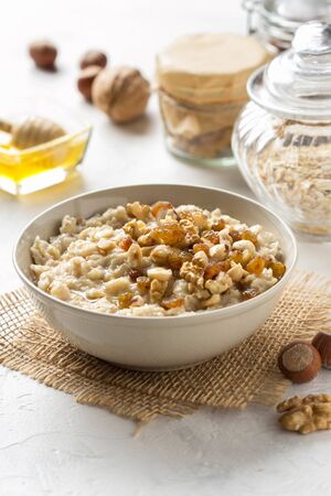 Oatmeal with nuts (hazelnuts, walnuts) and honey, porridge for Breakfast. Tasty and healthy foodの写真素材