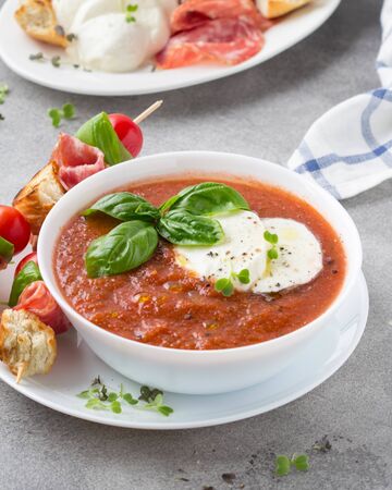 Tomato cold gazpacho soup with fresh vegetables, mozzarella, salami, croutons and basil. Traditional Spanish summer foodの写真素材