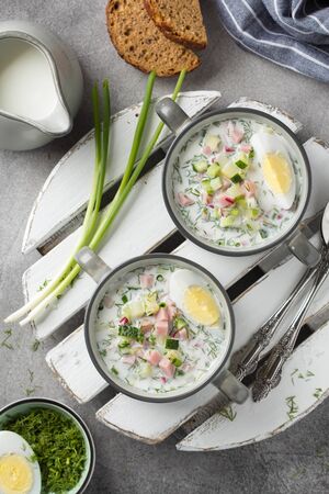 Traditional cold Russian soup okroshka, with sausage (ham), potatoes, boiled egg, fresh vegetables (cucumber, radish), green onions and dill. Yogurt, kefir, mineral water. Summer foodの写真素材