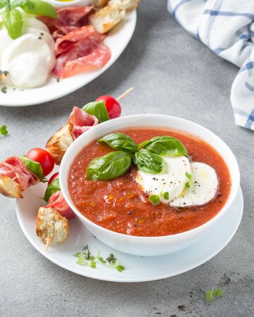 Tomato cold gazpacho soup with fresh vegetables, mozzarella, salami, croutons and basil. Traditional Spanish summer foodの写真素材