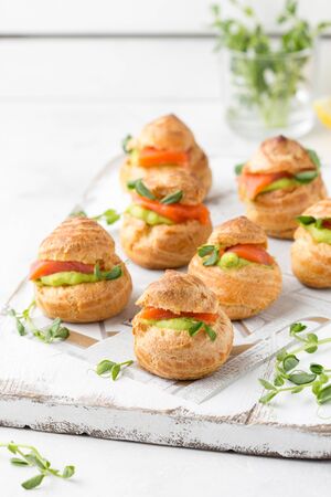 Snack cakes profiteroles with green pea cream and salmon red fish. Exquisite appetizer, a tasty lunch, traditional foodの写真素材