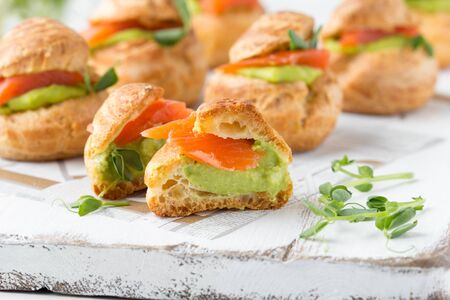 Snack cakes profiteroles with green pea cream and salmon red fish. Exquisite appetizer, a tasty lunch, traditional foodの写真素材