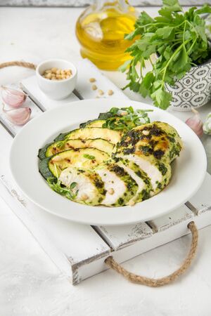 Grilled chicken fillet with green herb marinade, with slices of fried zucchini and pine nuts, delicious healthy lunchの写真素材