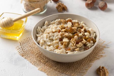 Oatmeal with nuts (hazelnuts, walnuts) and honey, porridge for Breakfast. Tasty and healthy foodの写真素材