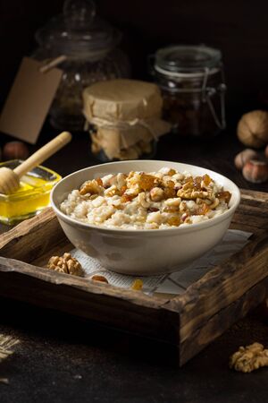 Oatmeal with nuts (hazelnuts, walnuts) and honey, porridge for Breakfast. Tasty and healthy foodの写真素材