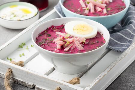 Cold beet soup, traditional Lithuanian dish, summer food. Fresh vegetables (cucumbers, radishes, green onions, cilantro), sour cream, yogurt, egg, hamの写真素材