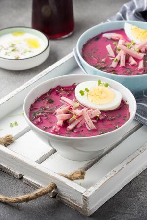 Cold beet soup, traditional Lithuanian dish, summer food. Fresh vegetables (cucumbers, radishes, green onions, cilantro), sour cream, yogurt, egg, hamの写真素材