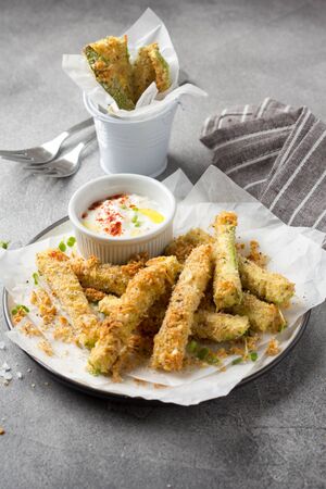 Zucchini sticks in breadcrumbs, with cheese, herbs, breadcrumbs and white yogurt sauce. Healthy tasty snack, summer foodの写真素材