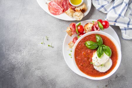 Tomato cold gazpacho soup with fresh vegetables, mozzarella, salami, croutons and basil. Traditional Spanish summer foodの写真素材