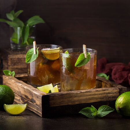 Whiskey Cola cocktail with lime, mint and ice in a glass. Rum, alcohol, Cuba Libre, brandy. Bar on dark backgroundの写真素材