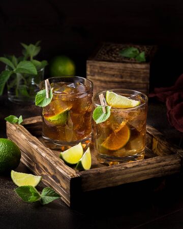 Whiskey Cola cocktail with lime, mint and ice in a glass. Rum, alcohol, Cuba Libre, brandy. Bar on dark backgroundの写真素材