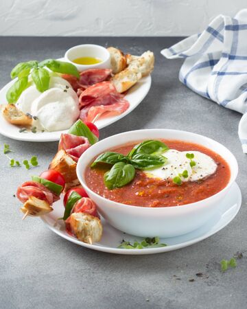 Tomato cold gazpacho soup with fresh vegetables, mozzarella, salami, croutons and basil. Traditional Spanish summer foodの写真素材