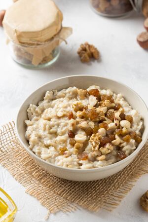 Oatmeal with nuts (hazelnuts, walnuts) and honey, porridge for Breakfast. Tasty and healthy foodの写真素材