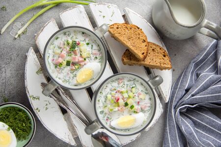 Traditional cold Russian soup okroshka, with sausage (ham), potatoes, boiled egg, fresh vegetables (cucumber, radish), green onions and dill. Yogurt, kefir, mineral water. Summer foodの写真素材