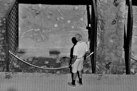 Elderly gentleman in front of the skeletons at the archaeological site of Eercolano, Salerno. Black white photoの写真素材