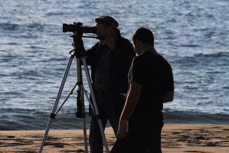 Movie set. Cameram and actor in backlight, seascape background at sunset