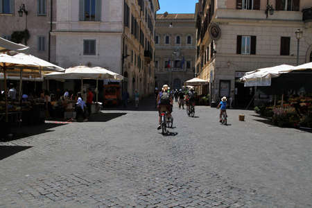 Glimpse of the Campo de Fiori square in Rome, summer day, people on bicycles.のeditorial素材