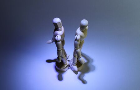 Overhead shot of two wooden mannequins facing opposite direction. Dominant blue color, shadows in the background.の写真素材