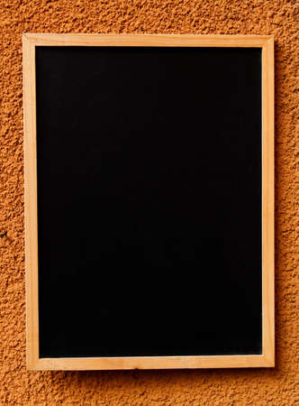 Blackboard with wooden frame hanging on orange wall.