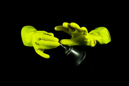 Hands with pink plastic gloves and and necklace with green stones, dark background.