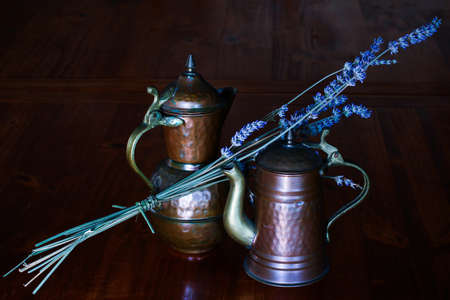 Small pewter jugs with a sprig of lavender placed on a wooden tableの写真素材