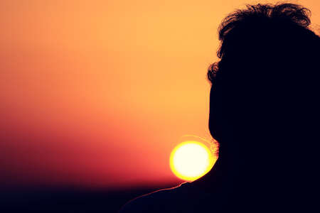 Practicing yoga at sunset, woman figure in backlight, mountains in the background.の写真素材