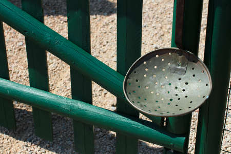 Antique kitchen utensil hanging on a green wooden gate.の写真素材